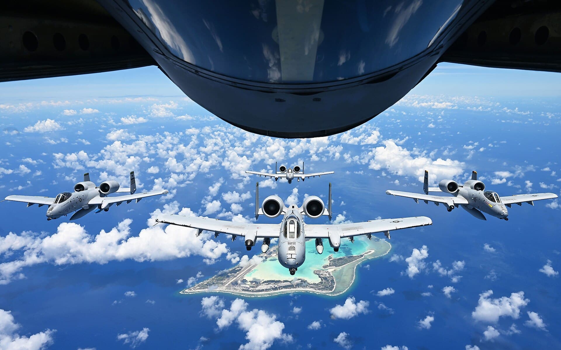 A formation of A-10 Thunderbolt II attack aircraft in flight above an island
