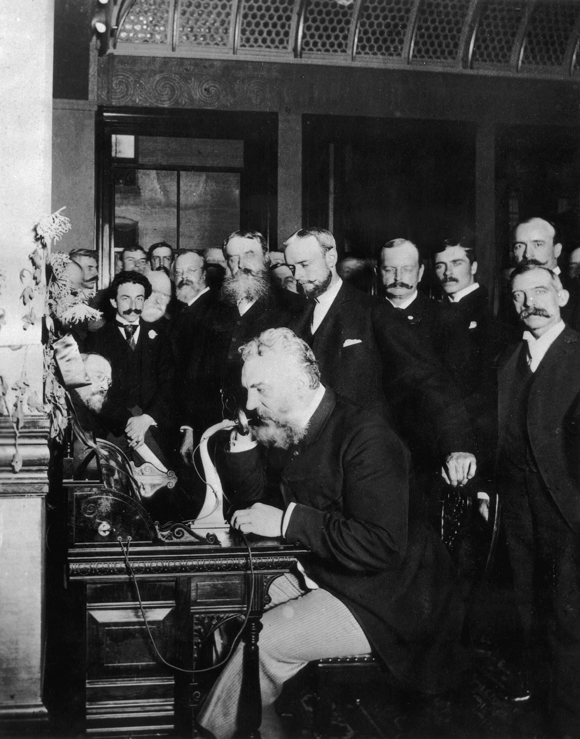 Alexander Graham Bell speaking into a telephone before a crowd to open a long-distance line
