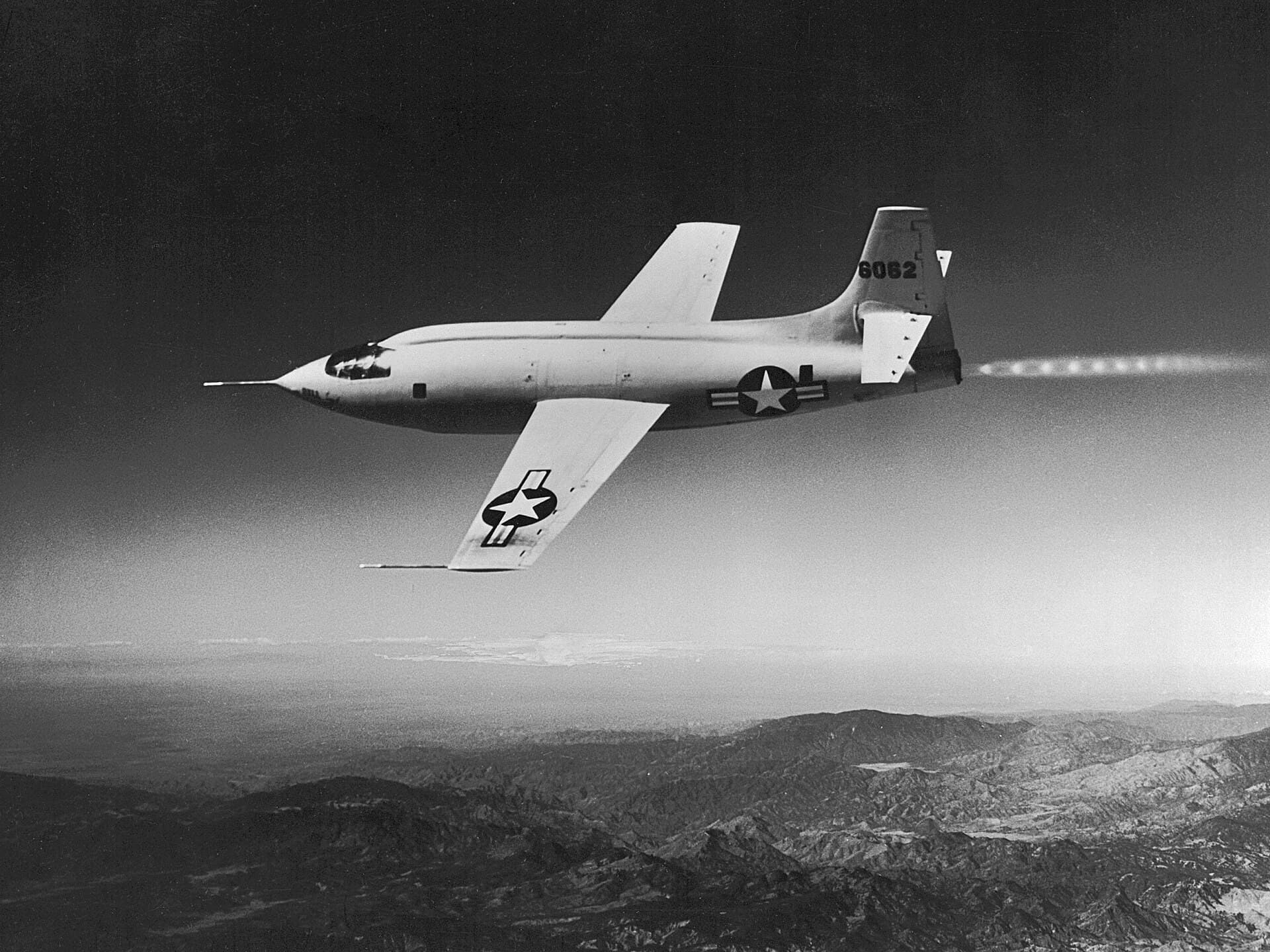 The Bell X-1 rocket plane in flight over mountains