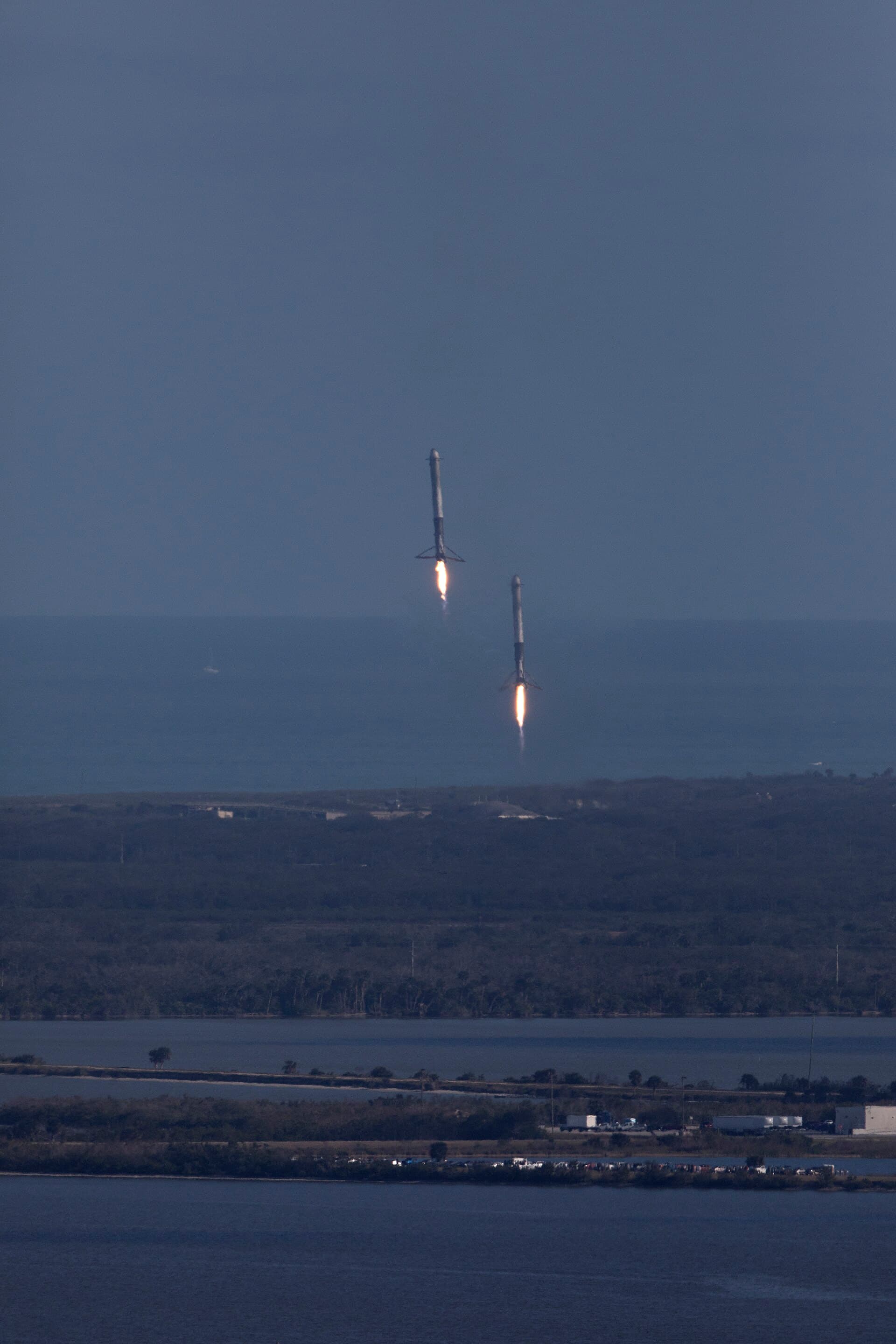 Two SpaceX Falcon Heavy side boosters descending under power toward synchronized landings