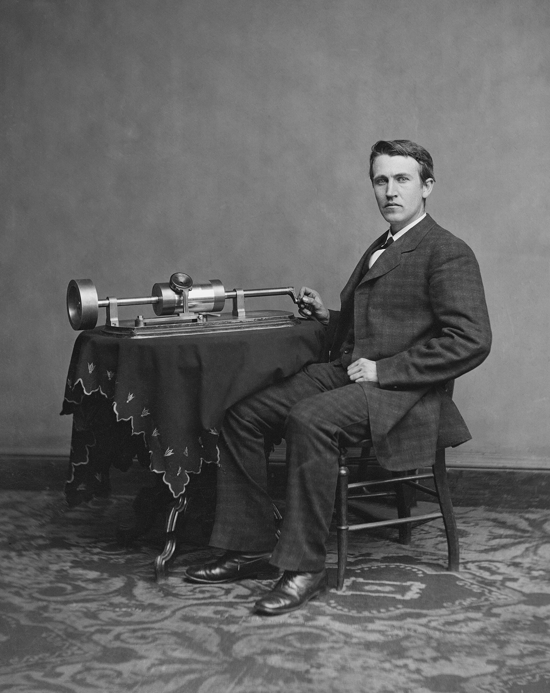 Portrait of a young Thomas Edison seated beside an early phonograph