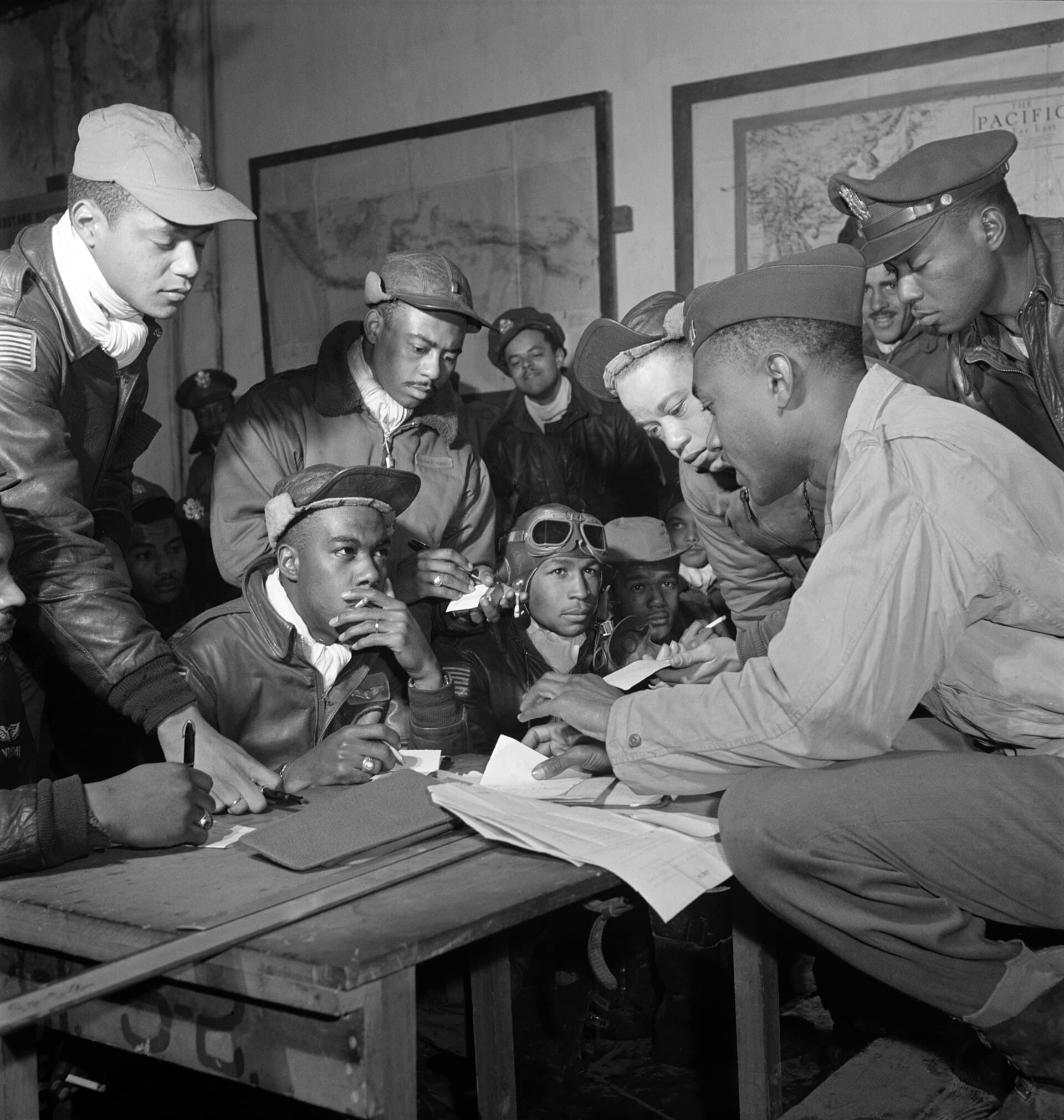 Tuskegee Airmen gathered around a table for a mission briefing