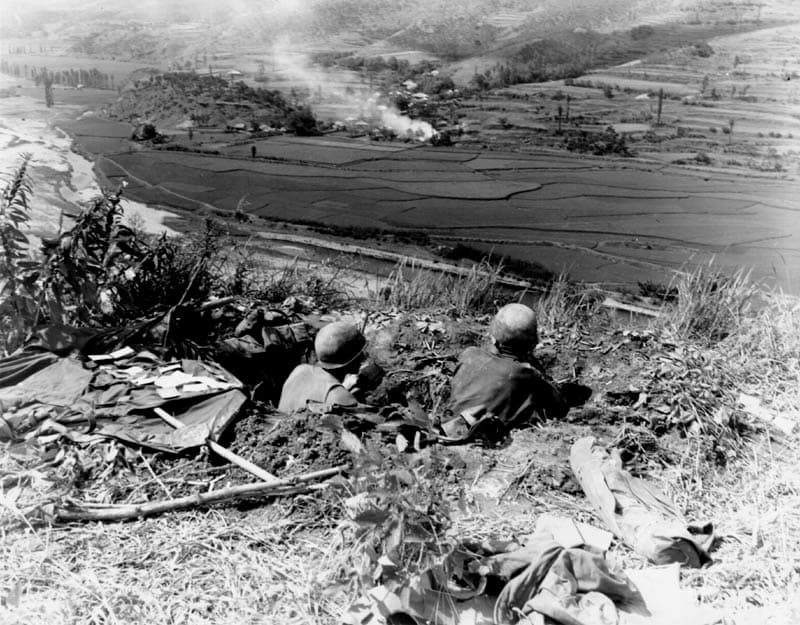 U.S. soldiers in a foxhole overlooking a valley while defending the Pusan Perimeter
