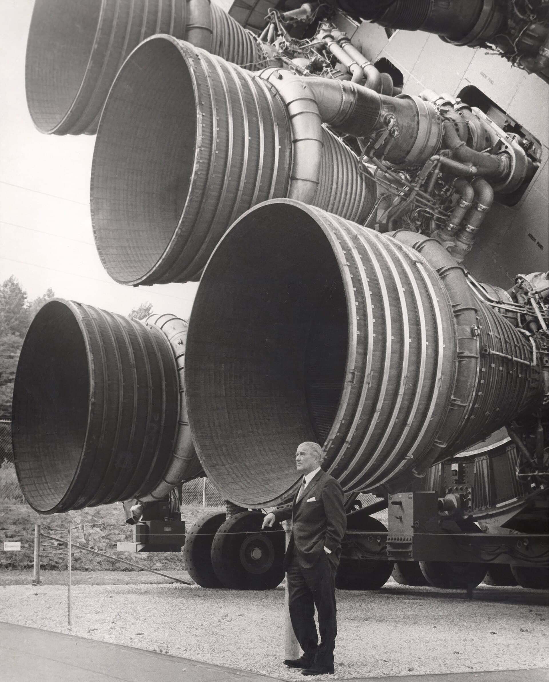 Wernher von Braun standing beside the five enormous F-1 engines of the Saturn V first stage